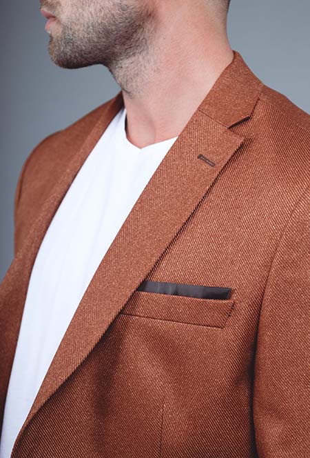 Détail du revers cranté et de la poche poitrine contrastée du blazer camel