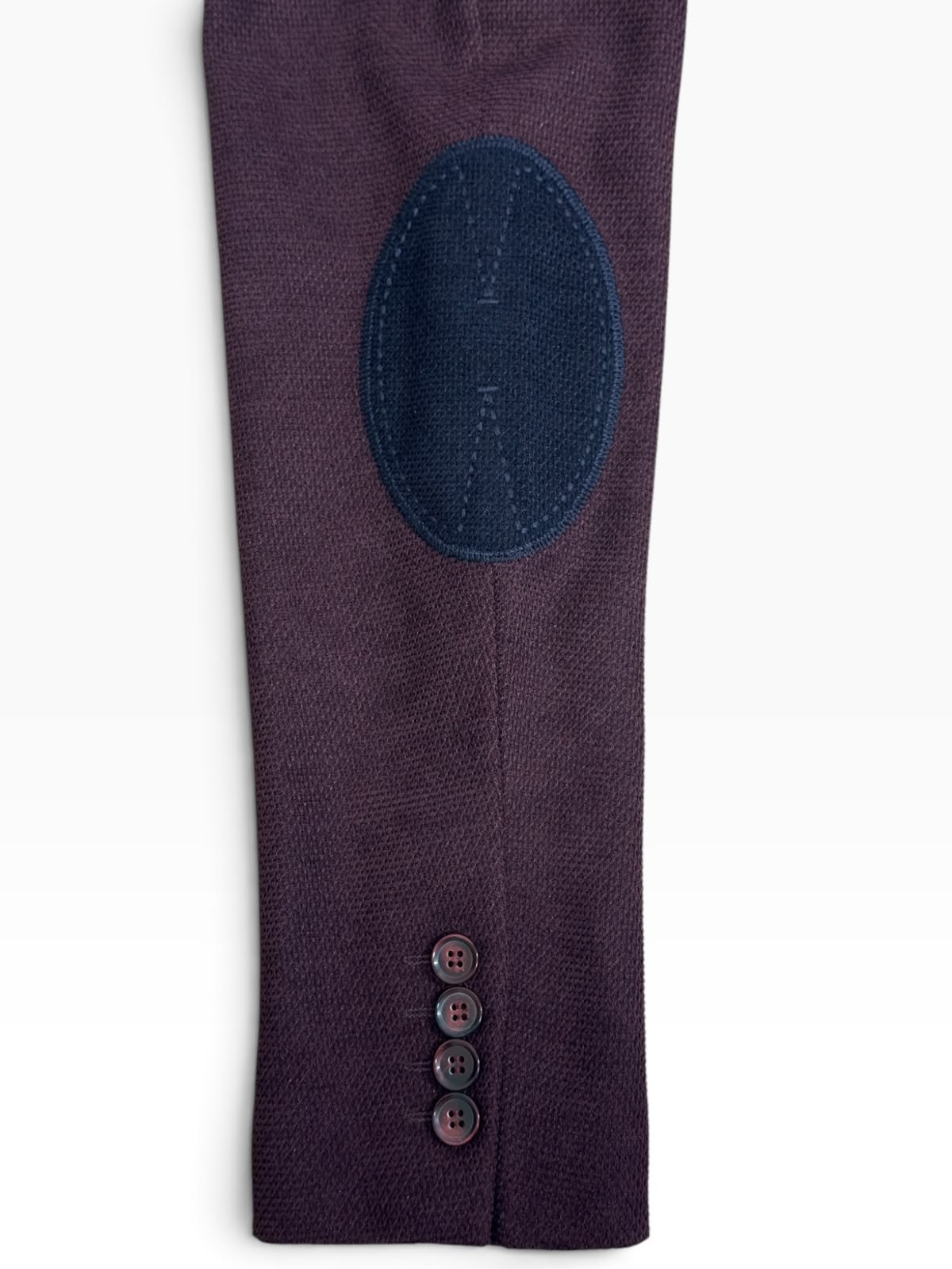 Détail de la coudière bleu marine surpiquée et des 4 boutons de manche du blazer bordeaux