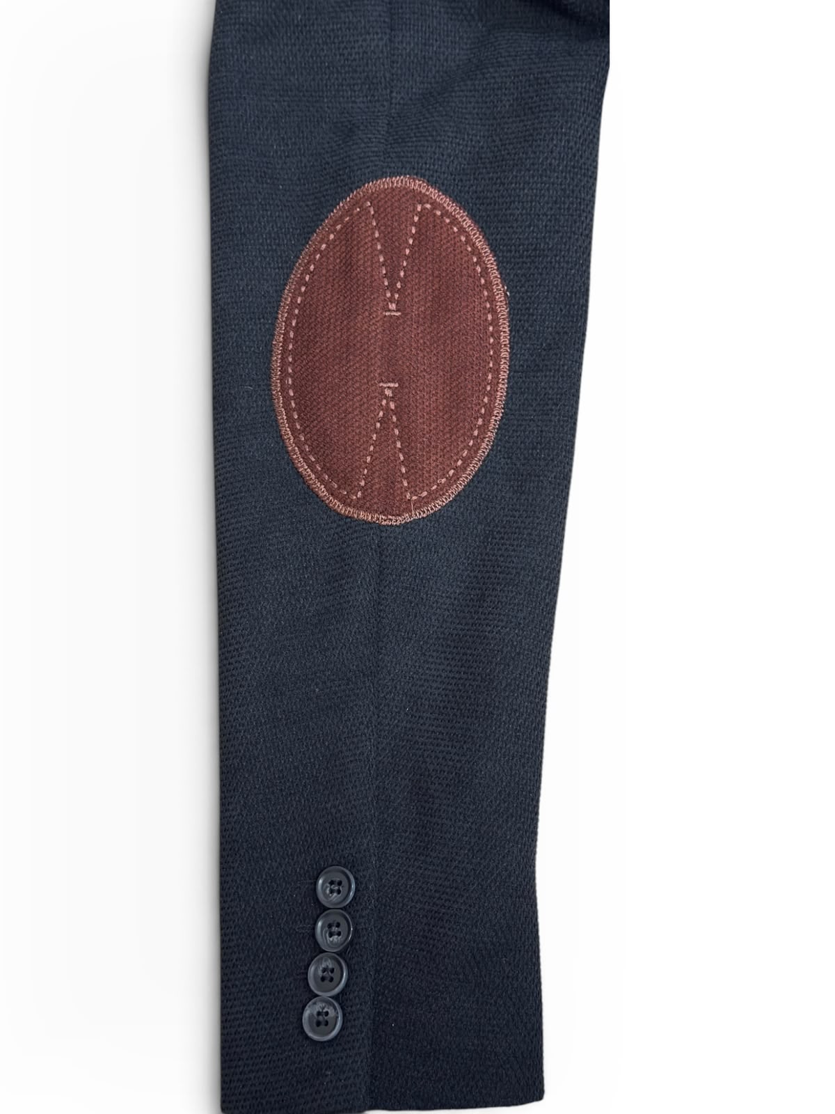 Détail de la coudière brique surpiquée et des boutons de manche du blazer noir